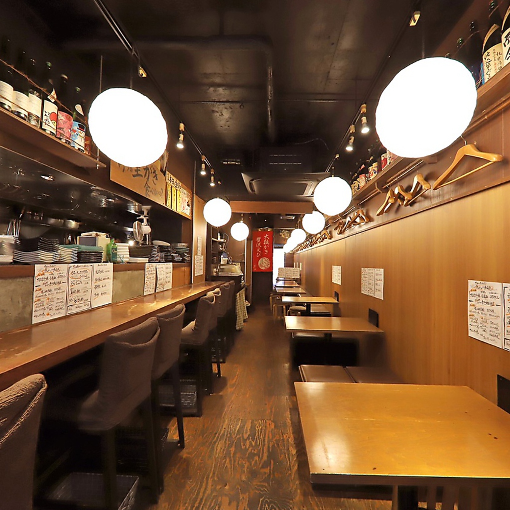 カウンターとテーブル、外にはテラス席もあり、旨そうな海鮮料理と日本酒が各テーブルを賑わせている