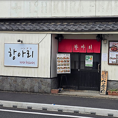 白壁と落ち着いた木目が印象的な外観は、和の雰囲気を感じさせながらも韓国料理店ならではの温かみを演出。赤い暖簾が目を引き、通りからも親しみやすい印象を与えます。入口横のメニュー看板で料理内容も確認でき、初めての方でも安心して立ち寄れる、居心地の良さを感じる一軒です。