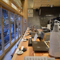 都会の夜を背に、回らない寿司をカウンターで楽しむ