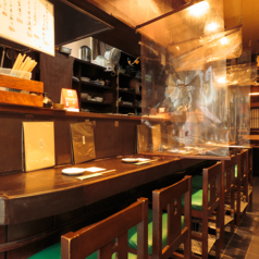 カップルに人気のカウンター席。昭和からあるしっかりとした造りのカウンター。タバコの煙等、隣を気にしないように吊り下げのパーティションあり