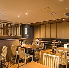 【テーブル席】明るい木目調で統一された清潔感あふれるテーブル席は、お買い物帰りの休憩やご家族での団らんに最適です。通路も広く確保されているため、ベビーカーのまま安心してご入店いただけます。九州の厳選食材を囲み、賑やかで楽しいひとときをお過ごしください！