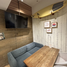 【サーフテイスト溢れるプライベート空間】ウッド調の壁とテーブルが温もりを感じさせるおしゃれな半個室。壁にはサーフボードやアートが飾られ、海辺のカフェのようなリラックスムードが漂います。ゆったりとしたソファ席で寛ぎながら、仲間や恋人と落ち着いた時間を過ごせるおすすめの空間です。